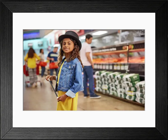Framed Print : Young girl with magicians top hat and wand standing in isle of busy grocery store, customers in line at the meat market in the background Framed Print : Young girl with magicians top hat and wand standing in isle of busy grocery store, customers in line at the meat market in the background