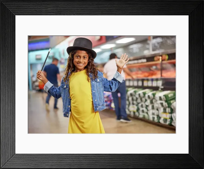 Framed Print : Young girl making big gesture with magicians top hat and wand standing in isle of busy grocery store, customers in line at the meat market in the background Framed Print : Young girl making big gesture with magicians top hat and wand standing in isle of busy grocery store, customers in line at the meat market in the background