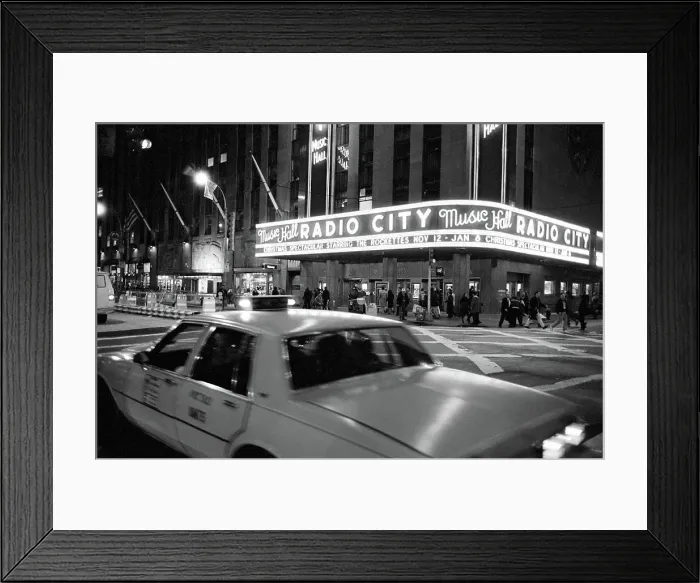 Framed Print : Taxi cab moving on a street in front of the Radio City Music Hall