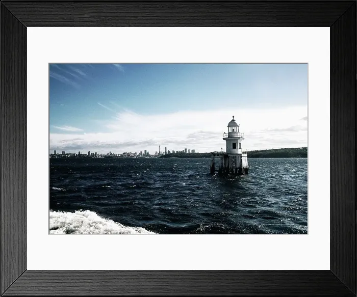 Framed Print : Lighthouse with buildings in the background
