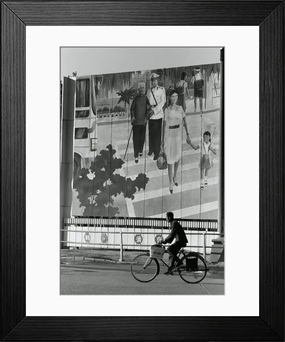 Framed Print : Man riding a bicycle in front of a mural, China Framed Print : Man riding a bicycle in front of a mural, China