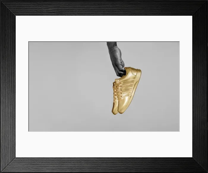 Framed Print : Yes. Desaturated / detail shot of Black man's hand holding gold painted sneakers Framed Print : Yes. Desaturated / detail shot of Black man's hand holding gold painted sneakers