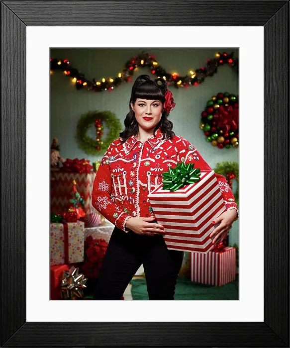 Framed Print : Portrait of woman with a retro hair style, in an 'ugly' Christmas sweater holding a present looking at the camera Framed Print : Portrait of woman with a retro hair style, in an 'ugly' Christmas sweater holding a present looking at the camera