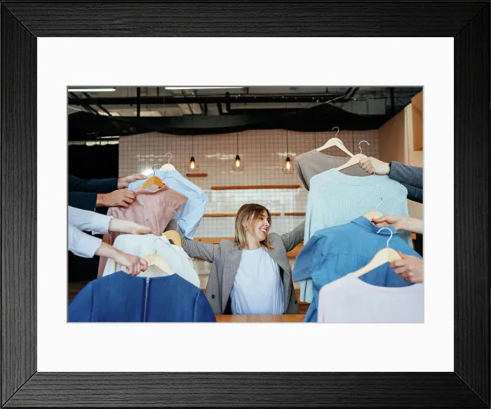 Framed Print : Young stylist looking through set of shirts for fashion shooting Framed Print : Young stylist looking through set of shirts for fashion shooting