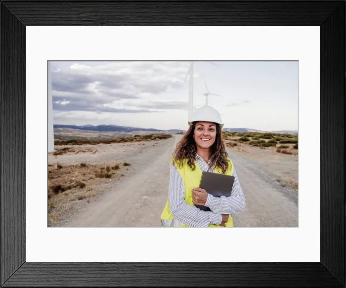 Framed Print : Smiling engineer wearing hardhat holding laptop at wind farm Framed Print : Smiling engineer wearing hardhat holding laptop at wind farm