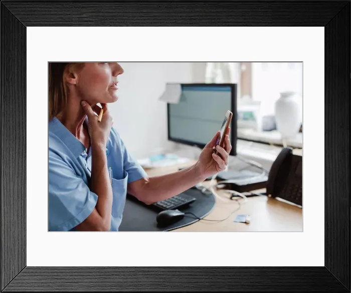 Framed Print : Female pediatrician using smart phone while explaining through video conference in office Framed Print : Female pediatrician using smart phone while explaining through video conference in office