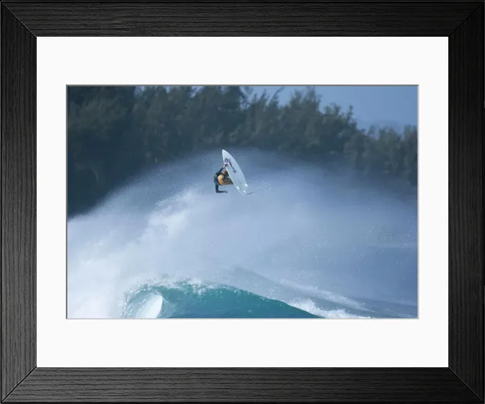 Framed Print : A young man performing a very high aerial maneuver, while surfing at Turtle Bay, Hawaii