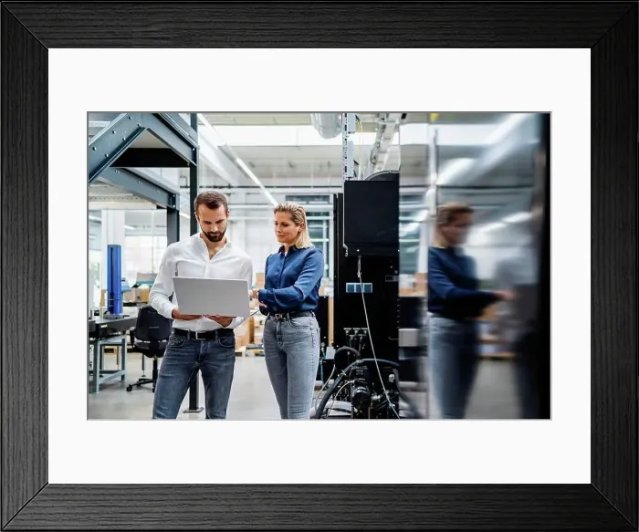 Framed Print : Business colleagues working on laptop standing in factory Framed Print : Business colleagues working on laptop standing in factory