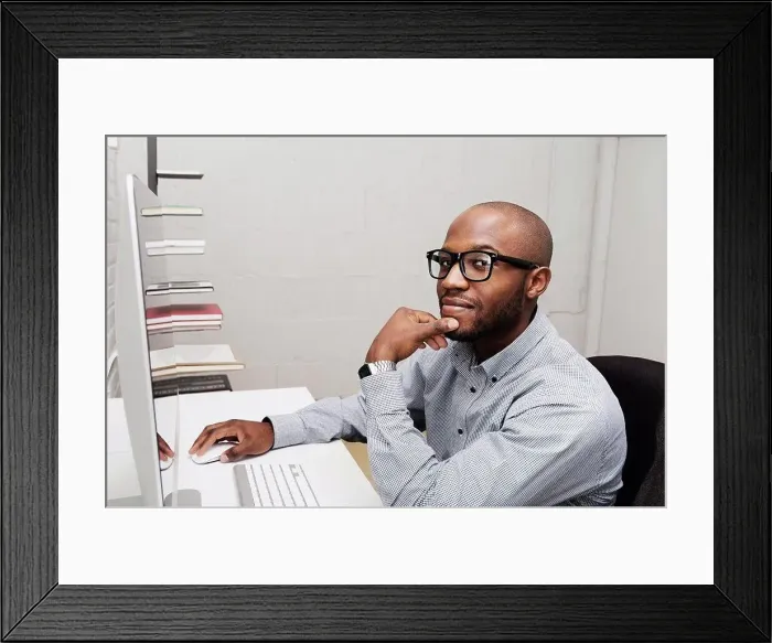 Framed Print : Portrait of young man using computer in design office Framed Print : Portrait of young man using computer in design office