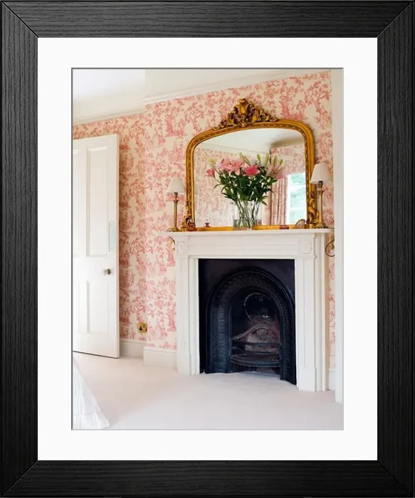 Framed Print : Large gilt mirror above fireplace in bedroom with pink Toile-de-Jouy wallpaper Framed Print : Large gilt mirror above fireplace in bedroom with pink Toile-de-Jouy wallpaper