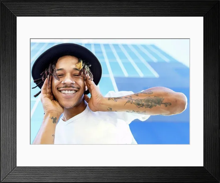Framed Print : Smiling man wearing hat standing against modern building in city