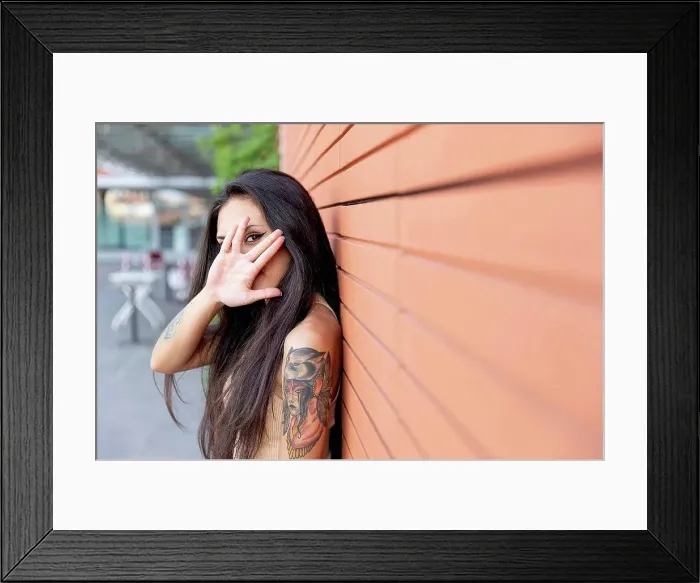 Framed Print : Woman looking through finger while leaning on wall Framed Print : Woman looking through finger while leaning on wall