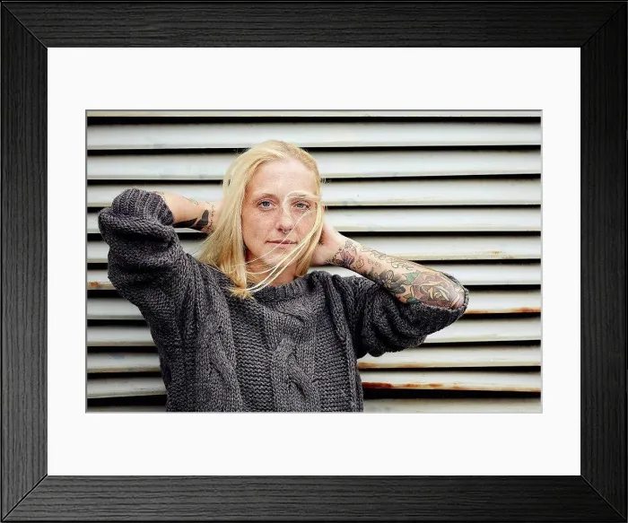 Framed Print : Tattooed woman with hand in hair standing in front of shutter Framed Print : Tattooed woman with hand in hair standing in front of shutter