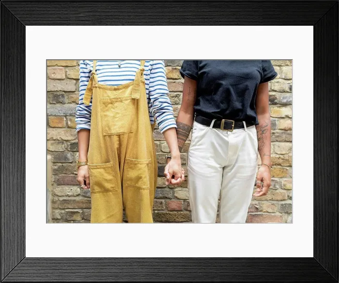 Framed Print : Young lesbian couple holding hands while standing against brick wall Framed Print : Young lesbian couple holding hands while standing against brick wall
