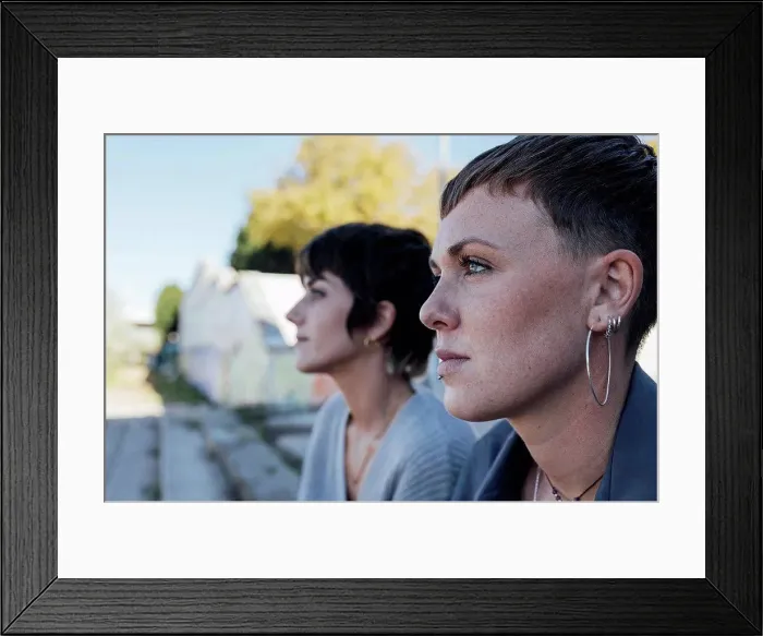 Framed Print : Young women looking away while sitting outdoors Framed Print : Young women looking away while sitting outdoors