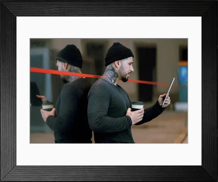 Framed Print : Tattooed hipster man with coffee cup using digital tablet while leaning on glass Framed Print : Tattooed hipster man with coffee cup using digital tablet while leaning on glass