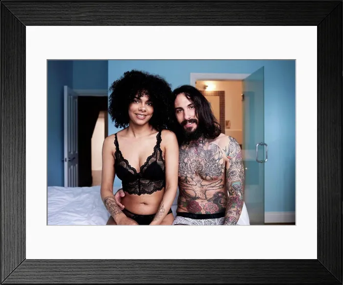 Framed Print : Portrait of smiling young couple sitting on bed