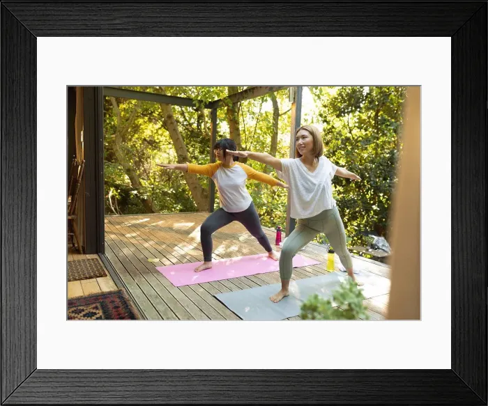 Framed Print : Smiling asian woman and her daughter practicing yoga on terrace in garden