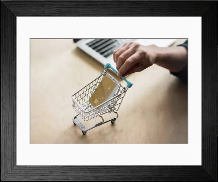Framed Print : Woman's hand holding mini shopping cart with credit card Framed Print : Woman's hand holding mini shopping cart with credit card