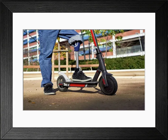 Framed Print : Disabled man with prosthetic leg standing on electric push scooter in playground Framed Print : Disabled man with prosthetic leg standing on electric push scooter in playground