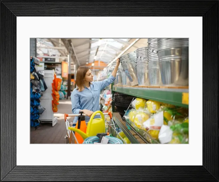 Framed Print : Female customer choosing metal bucket in shop for gardeners
