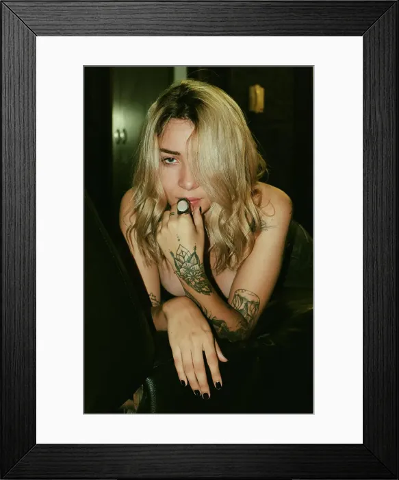 Framed Print : Seductive inviting fair haired tattooed woman in black bra and jeans sitting on sofa with legs spread wide Framed Print : Seductive inviting fair haired tattooed woman in black bra and jeans sitting on sofa with legs spread wide