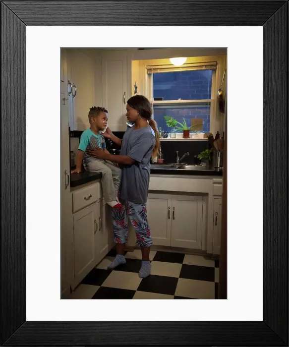 Framed Print : Mom at home in kitchen with son sitting on counter checking his temperature while talking to doctors on the phone