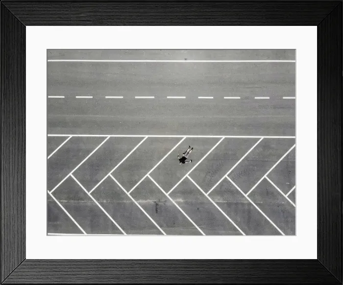 Framed Print : Drone view of man lying on back in empty parking lot Framed Print : Drone view of man lying on back in empty parking lot