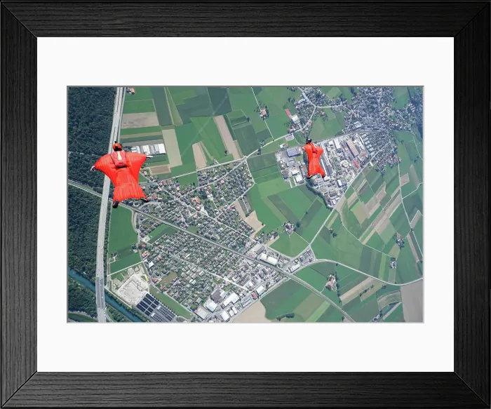 Framed Print : Aerial view of two wingsuit flyers in red suits flying above landscape