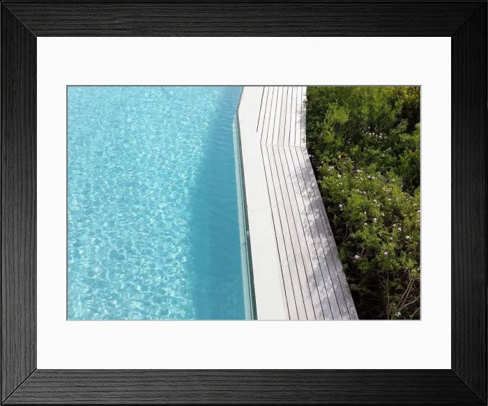Framed Print : Aerial view of a swimming pool with a paved edge and plants in a garden