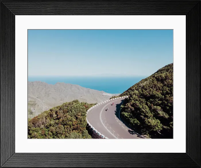 Framed Print : Aerial view of two cyclists on road bend in rain forest on sunny day Framed Print : Aerial view of two cyclists on road bend in rain forest on sunny day