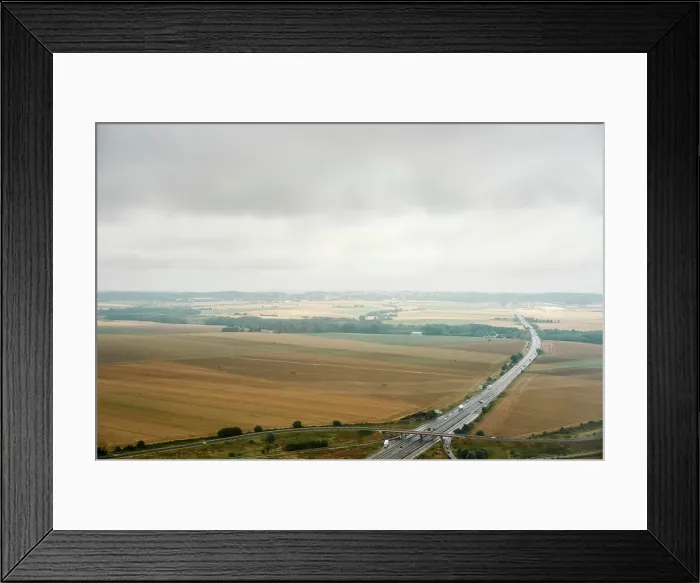 Framed Print : A tranquil aerial view of a highway slicing through the calm countryside under an overcast sky Framed Print : A tranquil aerial view of a highway slicing through the calm countryside under an overcast sky