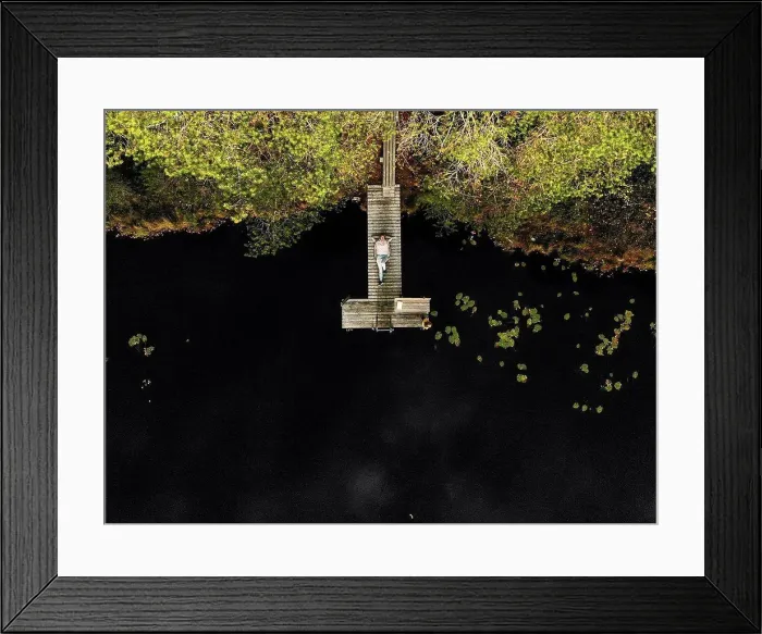 Framed Print : Aerial view of woman lying on pier over lake in forest Framed Print : Aerial view of woman lying on pier over lake in forest