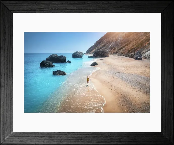 Framed Print : Aerial view of walking young woman on empty sandy beach near sea with waves at sunset Framed Print : Aerial view of walking young woman on empty sandy beach near sea with waves at sunset