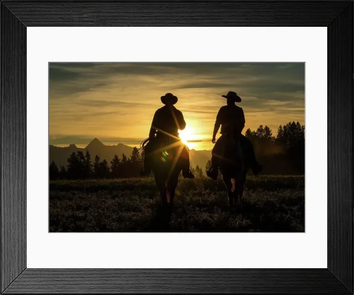 Framed Print : Two cowboys riding across grassland with mountains in background, early morning, British Colombia, Canada