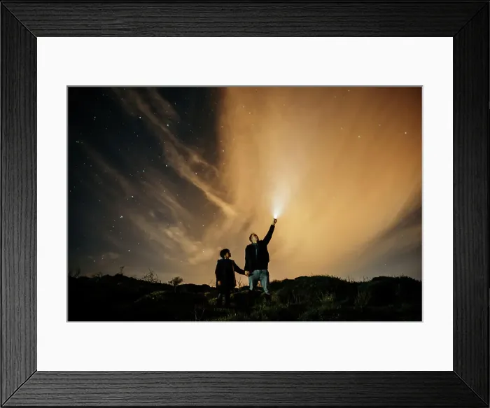 Framed Print : Carefree dad and son holding hands and observing starry sky while looking up and lighting with torch at night
