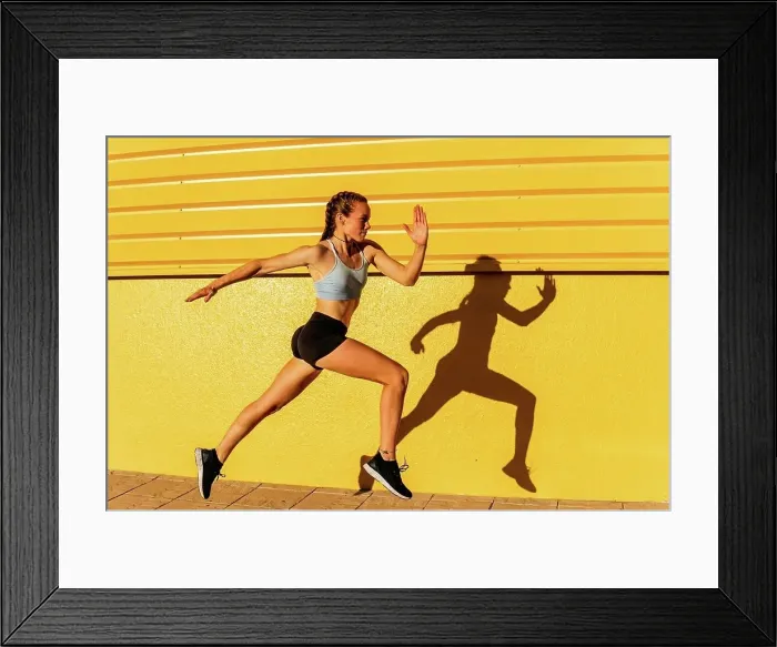 Framed Print : Young female athlete running by yellow wall Framed Print : Young female athlete running by yellow wall
