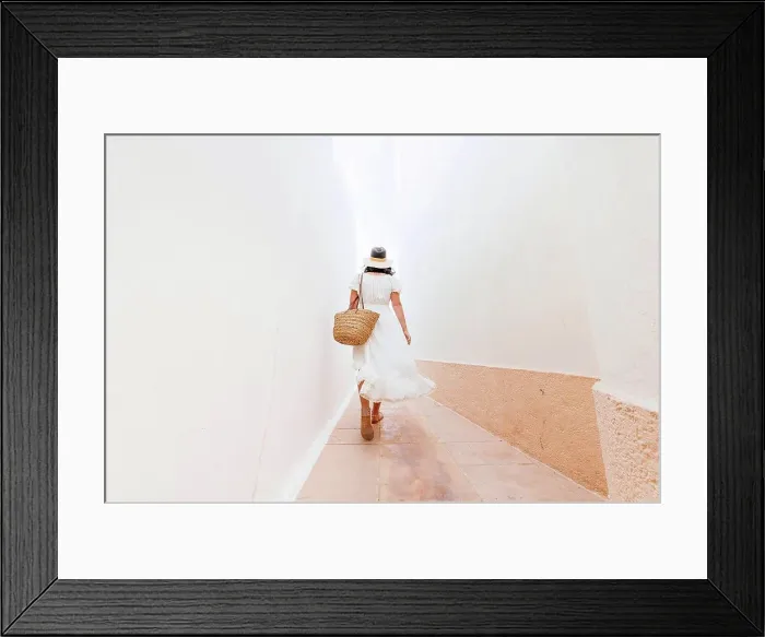 Framed Print : Mature woman wearing hat walking on footpath amidst walls Framed Print : Mature woman wearing hat walking on footpath amidst walls
