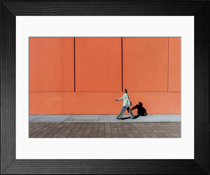 Framed Print : Young businesswoman with laptop walking by orange wall Framed Print : Young businesswoman with laptop walking by orange wall
