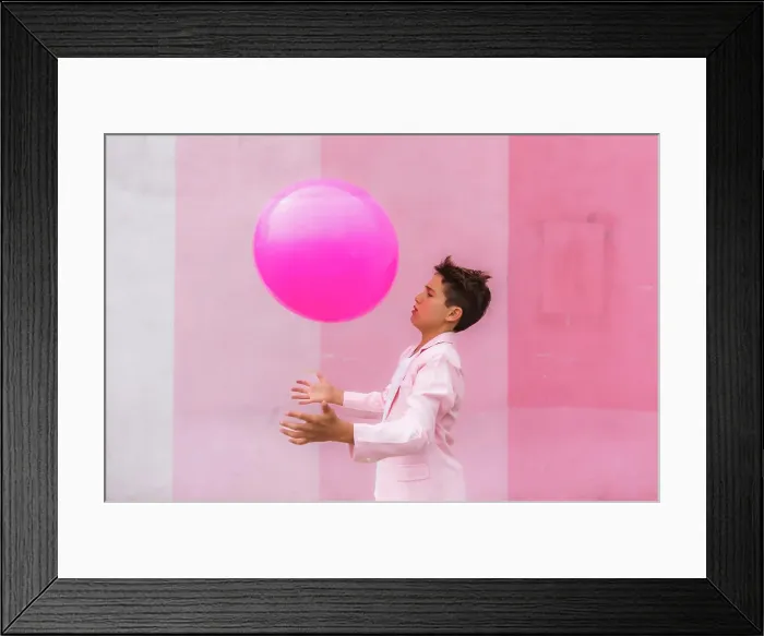 Framed Print : Young boy all pink playing with a ball on the sidewalk in a suit