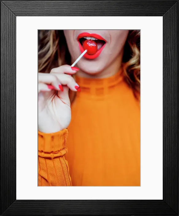 Framed Print : Pretty woman red lips eating a candy