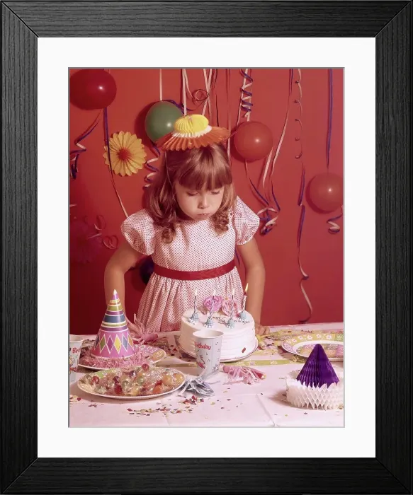 Framed Print : Girl blowing out candles on a birthday cake