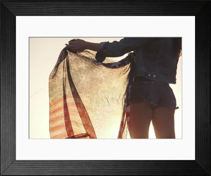 Framed Print : Woman wearing denim shorts, holding American flag, mid section, rear view