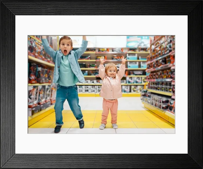 Framed Print : Little boy and girl raised their hands up at the shelf in kids store Framed Print : Little boy and girl raised their hands up at the shelf in kids store
