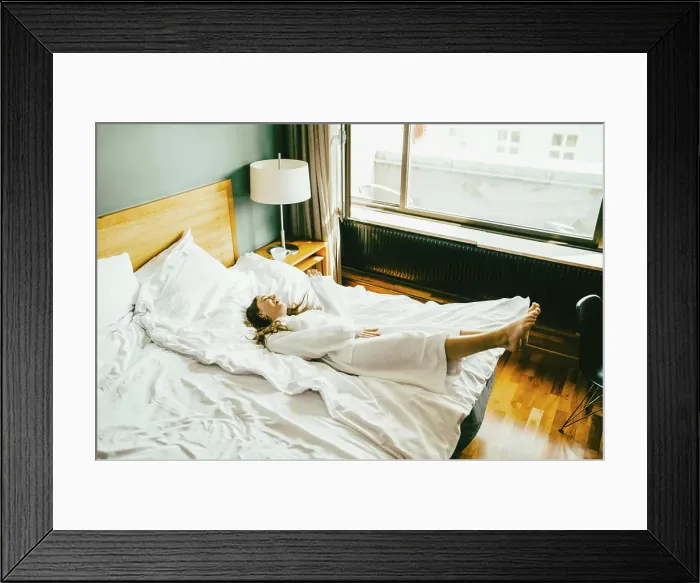 Framed Print : Smiling woman in bathrobe having fun on bed at hotel room Framed Print : Smiling woman in bathrobe having fun on bed at hotel room