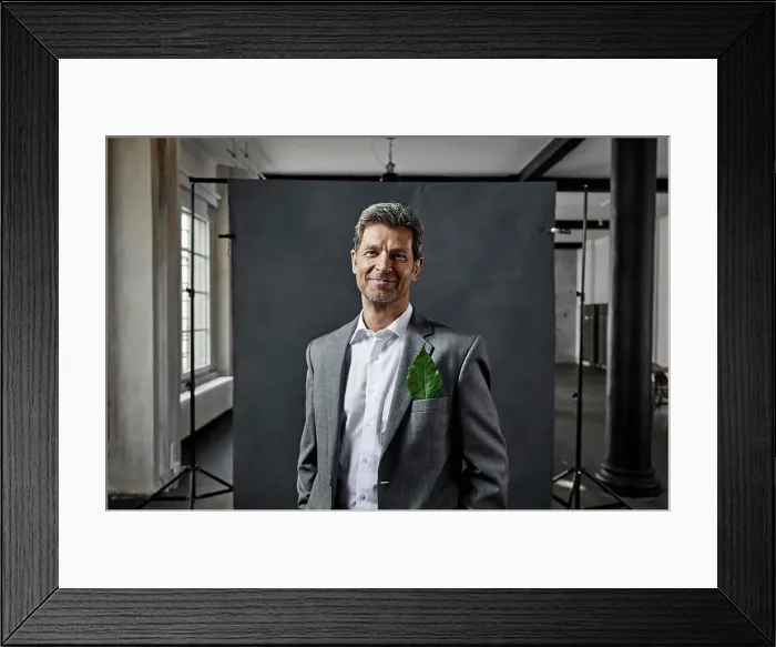 Framed Print : Portrait of mature businessman with leaf in pocket in front of black backdrop in loft