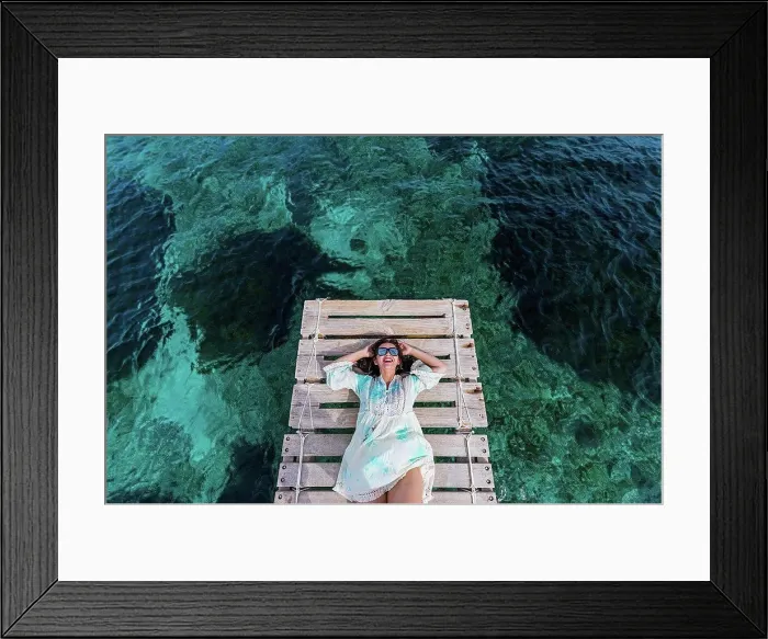 Framed Print : Happy woman wearing sunglasses lying on jetty amidst water Framed Print : Happy woman wearing sunglasses lying on jetty amidst water