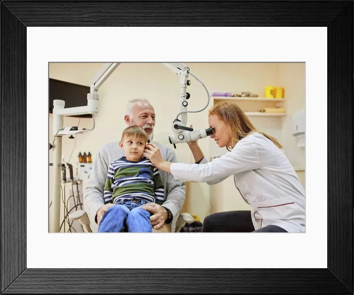 Framed Print : ENT physician examining ear of a boy sitting on grandfather's lap Framed Print : ENT physician examining ear of a boy sitting on grandfather's lap
