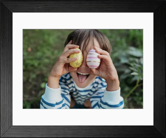 Framed Print : Boy sticking out tongue and cover eyes with easter eggs in park Framed Print : Boy sticking out tongue and cover eyes with easter eggs in park