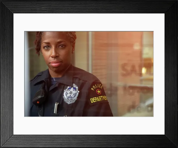 Framed Print : Portrait of Police woman standing in front of large glass window with reflections looking towards camera Framed Print : Portrait of Police woman standing in front of large glass window with reflections looking towards camera